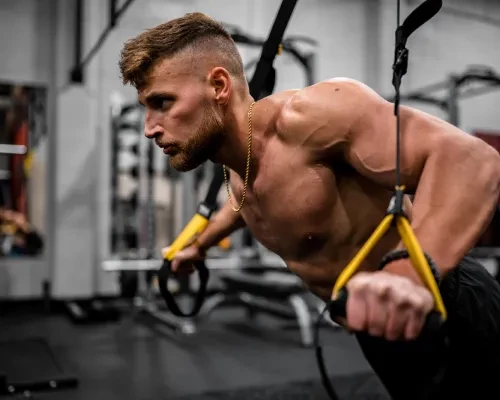Homme exerçant des tractions avec des sangles de TRX au club de sport FITNESS MORTEAU 25500.